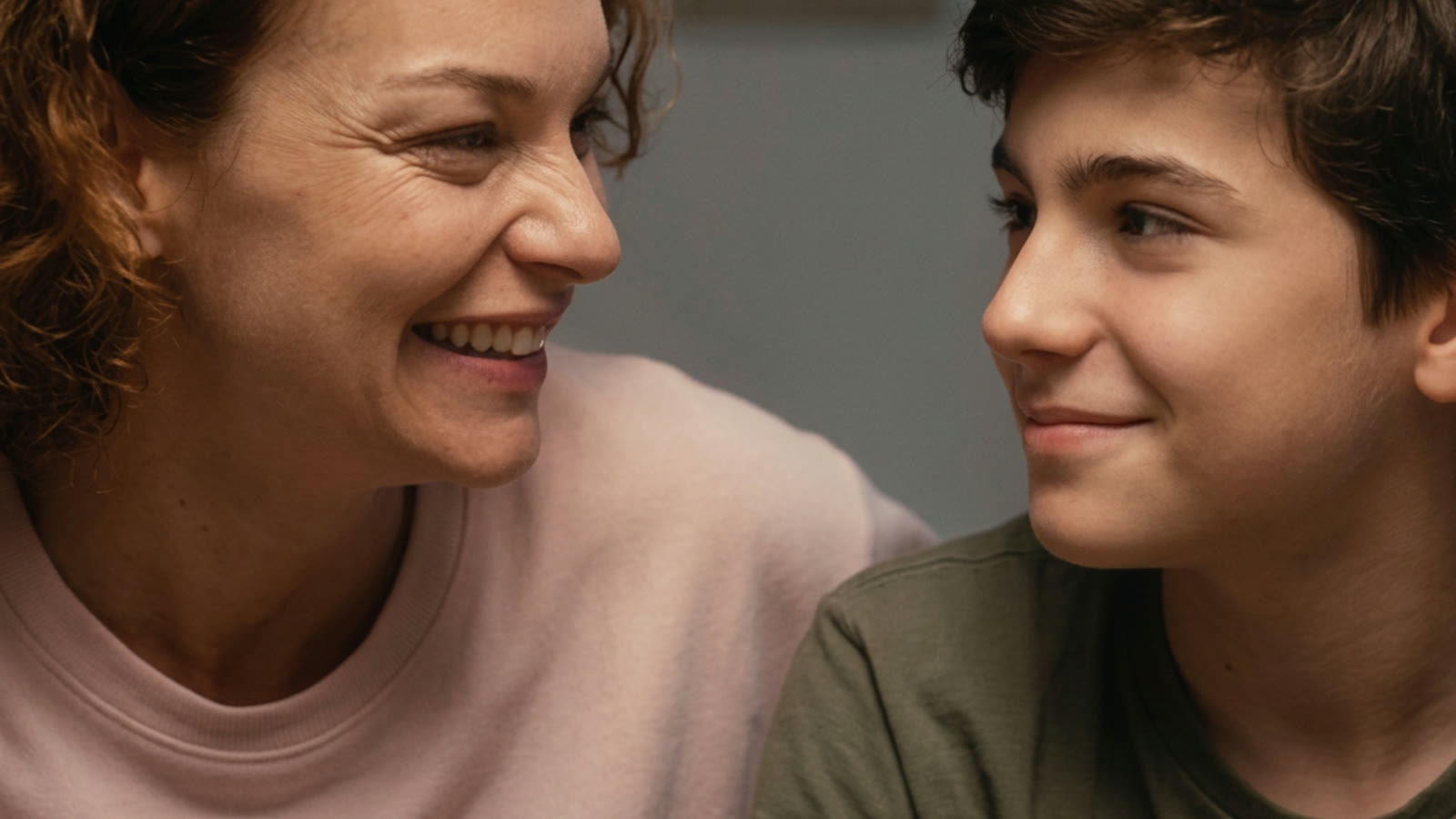 Mãe e filho adolescente sorrindo lado a lado